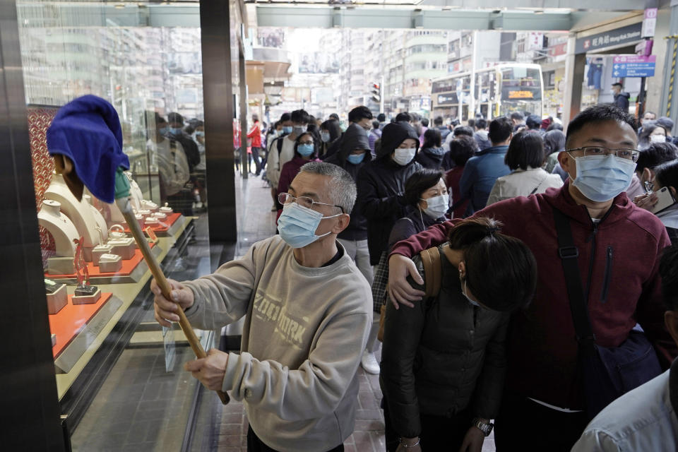 A worker cleans a window of a jewelry shop as people queue to buy face masks in Hong Kong, Saturday, Feb, 1, 2020. China’s death toll from a new virus has risen over 250 and a World Health Organization official says other governments need to prepare for“domestic outbreak control” if the disease spreads. (AP Photo/Kin Cheung)