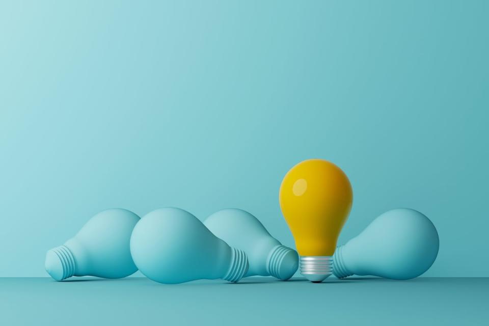 A yellow light bulb among a group of light blue light bulbs.