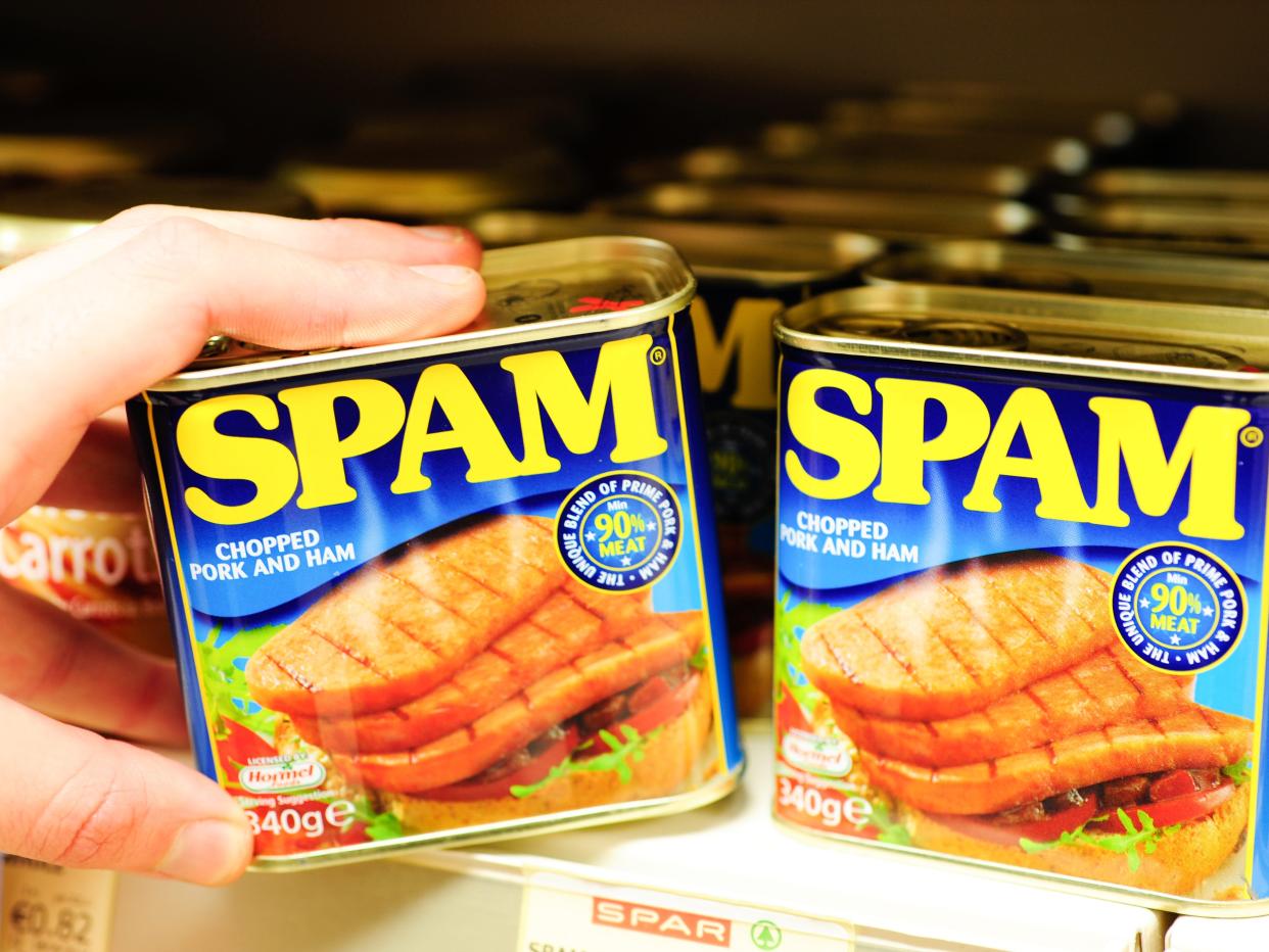 Photo of a can of spam being taken from a supermarket shelf