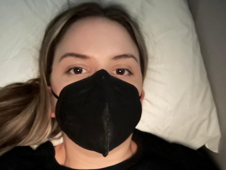 Collette Reitz with a mask on lying in bed