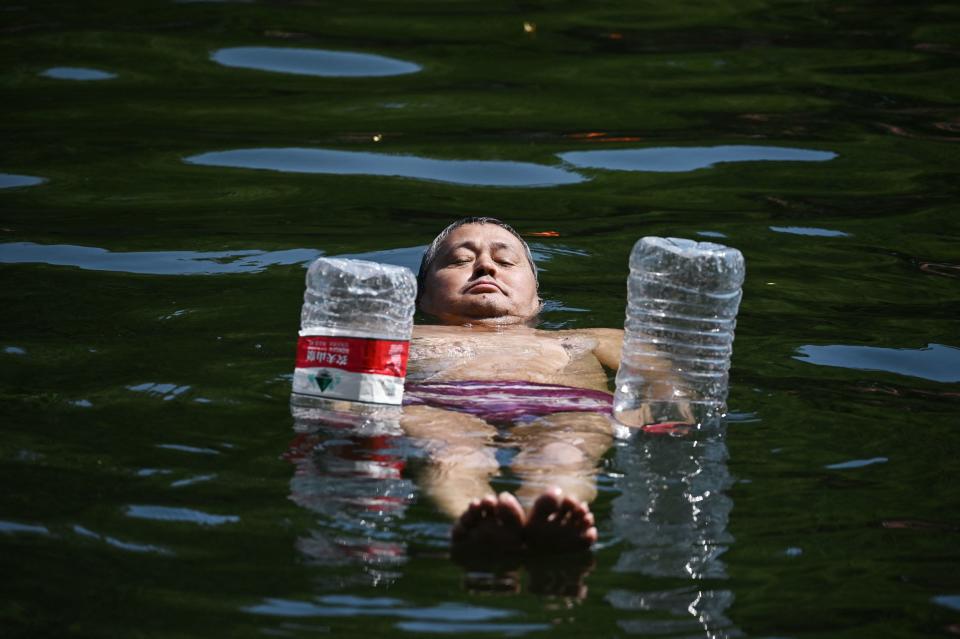 TOPSHOT - A man uses water bottles for flotation as he cools off in a canal in Beijing on June 22, 2023. Swathes of northern China sweltered in 40-degree heat on June 22, weather data showed, as parts of Beijing and the nearby megacity of Tianjin recorded their highest temperatures for years. (Photo by GREG BAKER / AFP) (Photo by GREG BAKER/AFP via Getty Images)