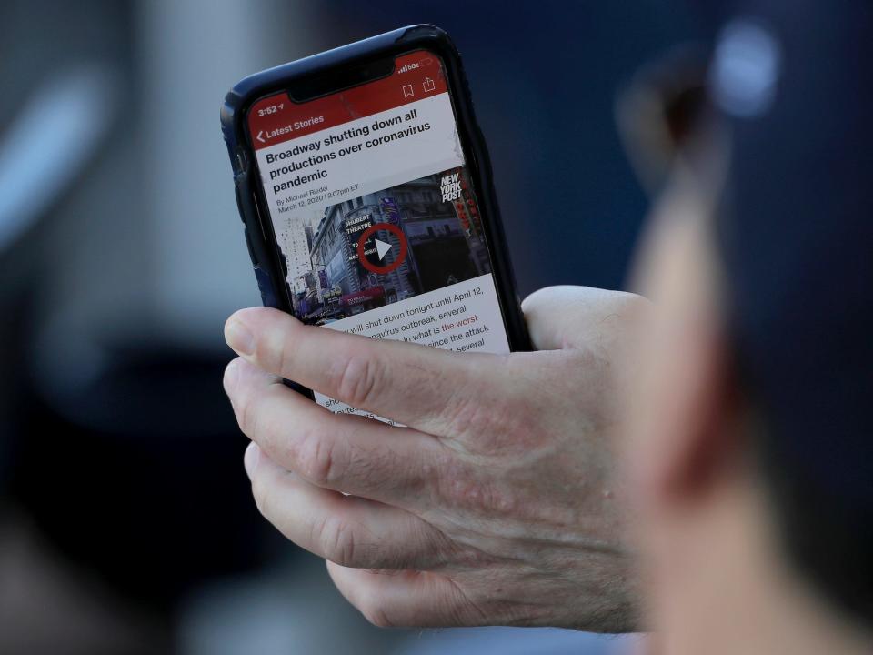 A person shows a man a news story on their phone.