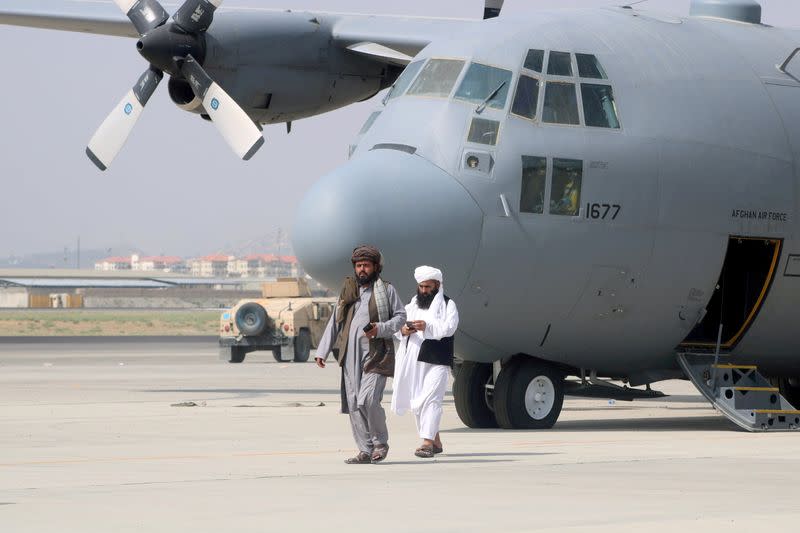 FILE PHOTO: Taliban walk in front of a military airplane a day after the U.S. troops withdrawal from Hamid Karzai International Airport in Kabul