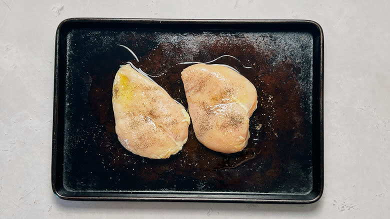 seasoned raw chicken on sheet tray