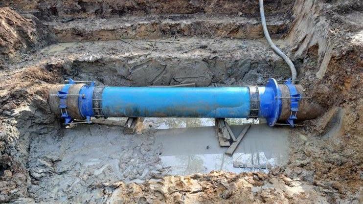 A blue plastic pipe surrounded by mud