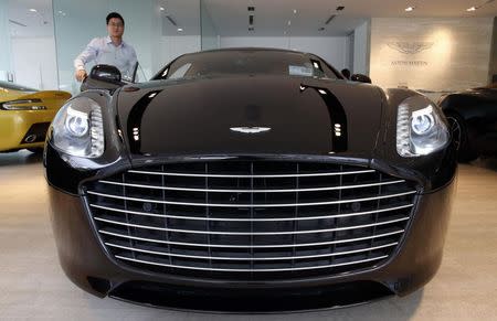 Sales Manager Raymond Liu switches on the headlights of an Aston Martin Vanquish at their showroom in Singapore August 1, 2014. REUTERS/Edgar Su