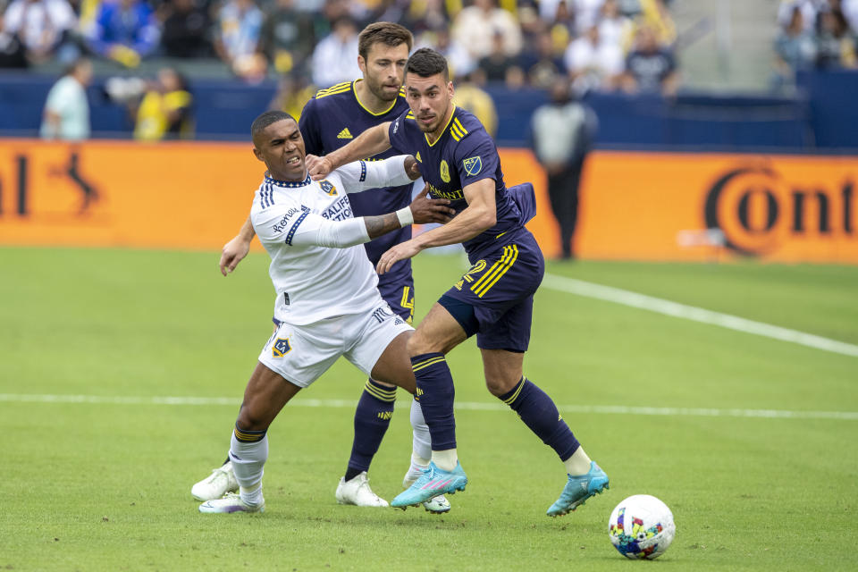 LA Galaxy forward Douglas Costa, left, vies for the ball with Nashville SC defenders Daniel Lovitz, right, and Dave Romney during the first half of an MLS playoff soccer match, in Carson, Calif., Saturday, Oct. 15, 2022. (AP Photo/Alex Gallardo)