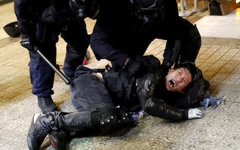 A demonstrator is detained by police officers  - Credit: &nbsp;KAI PFAFFENBACH/&nbsp;REUTERS