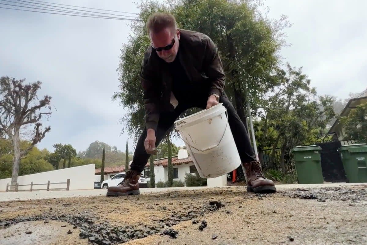 Former California Governor Arnold Schwarzenegger repairing a pot hole on a street in his Los Angeles neighbourhood (AP)