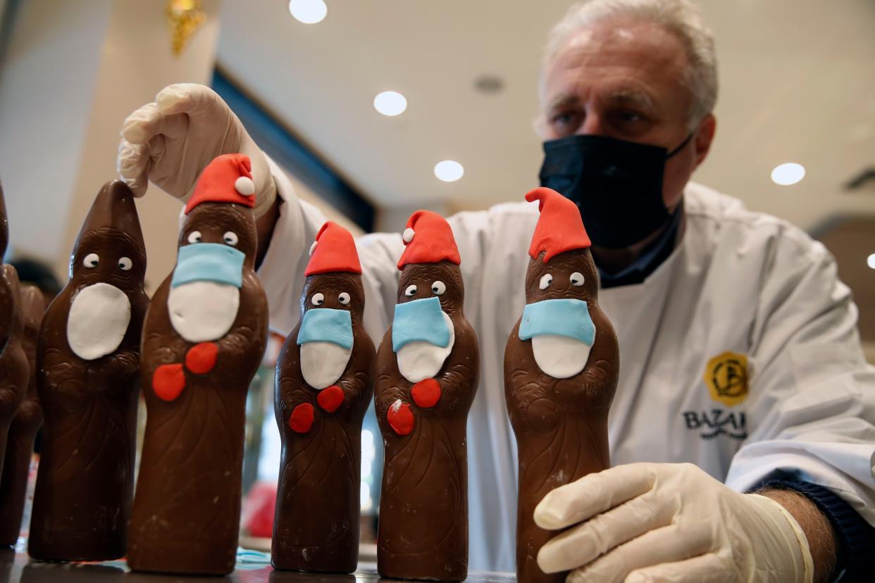 Tassos Vazakas owner of a cake shop prepares chocolate Santa Clauses with masks ahead of Christmas in Lykovrisi, northern Athens, Greece on Wednesday, Dec. 2, 2020. Cake shops and bakeries in Greece have remained open as officials said Monday that the number of new infections in COVID-19 is waning in most parts of the country, which has been in lockdown for three weeks.