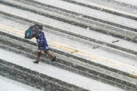 <p>A pedestrian races across the snow covered and tire streaked street in Washington during a spring storm, Wednesday, March 21, 2018. (Photo: J. David Ake/AP) </p>