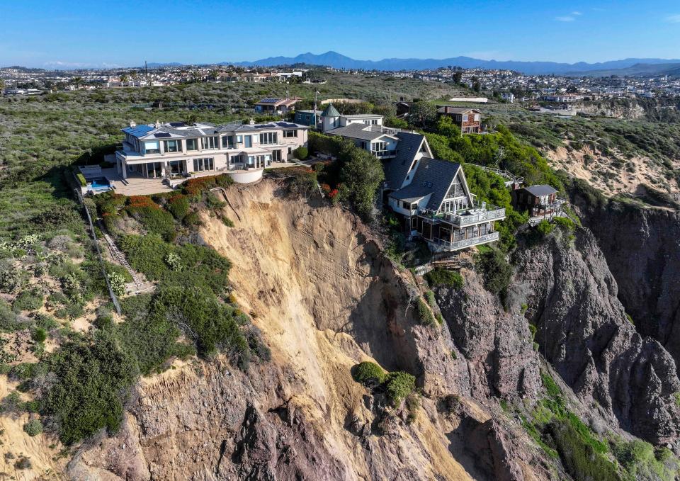 Cliff-top houses along Scenic Drive sit close to a landslide in Dana Point, Calif., on Tuesday, Feb. 13, 2024. The three homes affected by the recent deluge of rain across Orange County are being monitored but don't appear to be in imminent danger, county officials said.