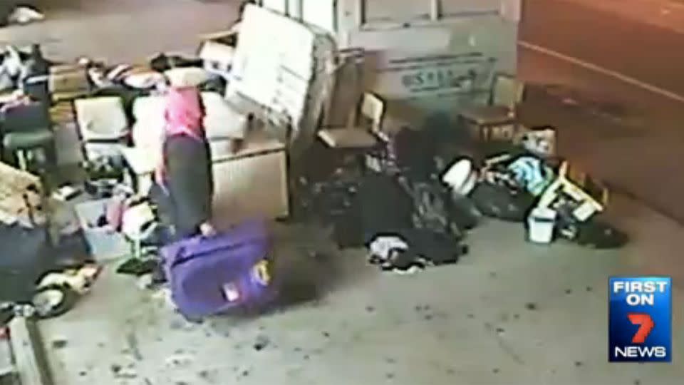 A woman can be seen fulling a purple suitcase full of stolen goods. Photo: 7 News