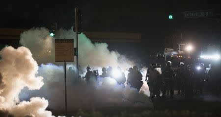 Riot police clear a street with smoke bombs while clashing with demonstrators in Ferguson, Missouri August 13, 2014. REUTERS/Mario Anzuoni