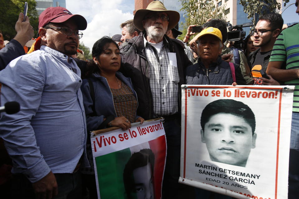 Poet and activist Javier Sicilia, center, stands with the relatives of 43 students that went missing in Sept. 2014, during a march against violence called "Walk for Peace," in Mexico City, Sunday, Jan. 26, 2020. Sicilia, accompanied by more than a hundred members of the LeBaron family, led his second march against violence in Mexico, with the group gathering supporters as it made its way towards Mexico City's main square the Zocalo. (AP Photo/Ginnette Riquelme)