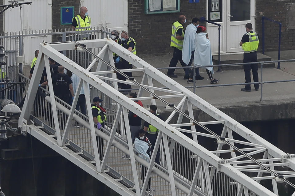 A group of people thought to be migrants are escorted by Border Force staff into the port city of Dover, England, from small boats, Saturday Aug. 8, 2020. The British government says it will strengthen border measures as calm summer weather has prompted a record number of people to attempt the risky sea crossing in small vessels, from northern France to England. (AP Photo/Kirsty Wigglesworth)