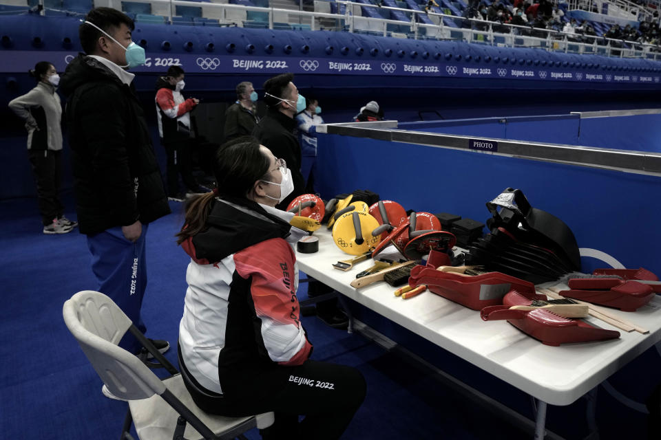 Olympic staff workers watch China's team compete during their mixed doubles curling match Switzerland, at the 2022 Winter Olympics, Wednesday, Feb. 2, 2022, in Beijing. (AP Photo/Nariman El-Mofty)