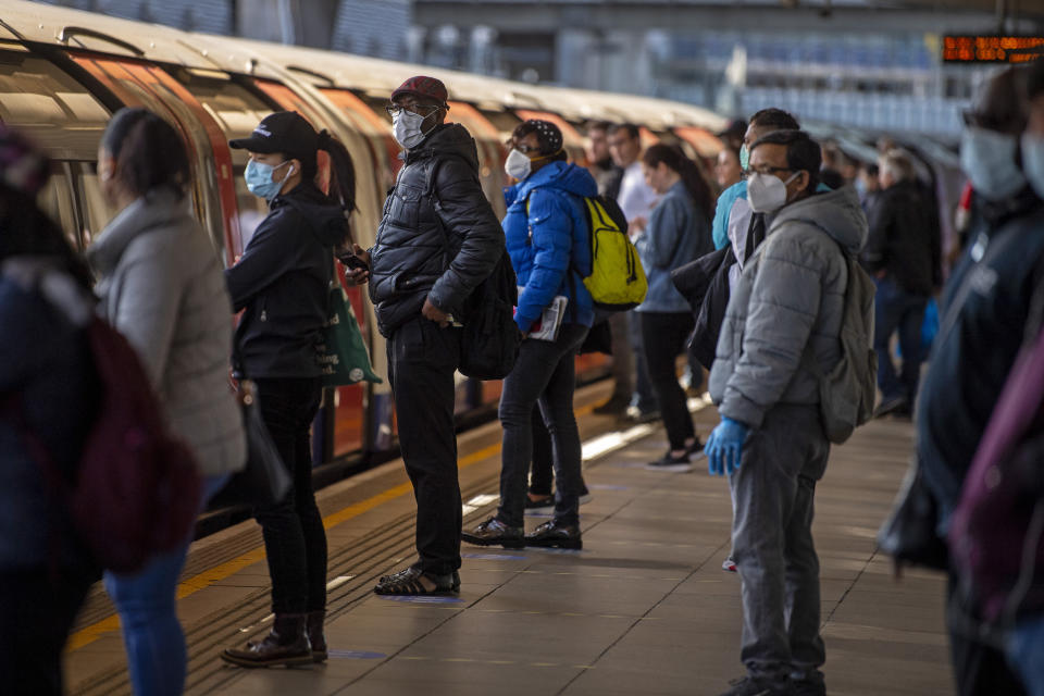 Passengers wearing face masks on a platform at Canning Town underground station in London.