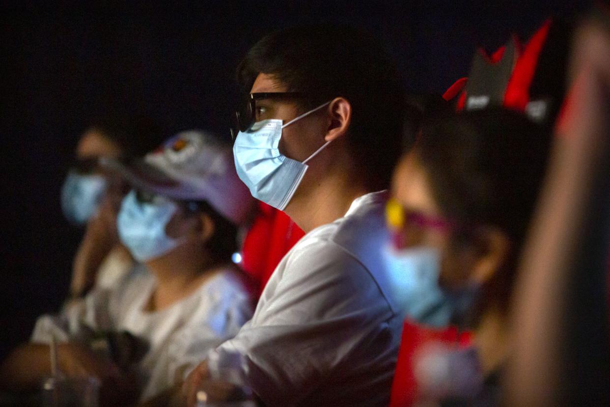 People wearing face masks to protect against the coronavirus watch the film "Dolittle" at a movie theater in Beijing on July 24, 2020.