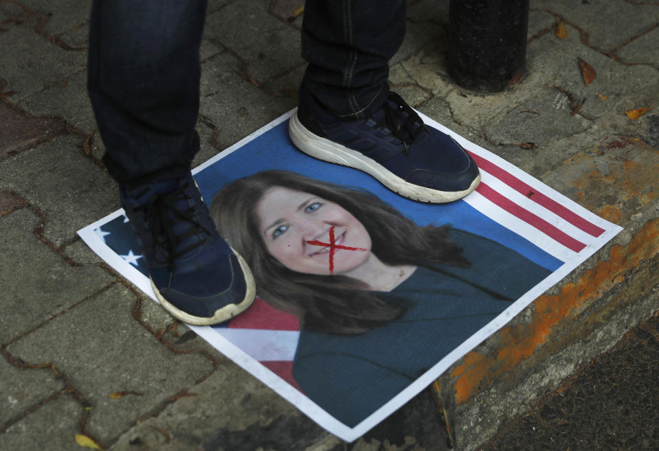 A protester stands on a portrait of the U.S. Ambassador to Lebanon Dorothy Shea, outside the Lebanese Foreign Ministry, in Beirut, Lebanon, Monday, June 29, 2020. Lebanon's foreign minister and the U.S. ambassador to Beirut discussed Monday a court ruling issued over the weekend in which a Lebanese judge banned local and foreign media outlets in the country from interviewing the ambassador for a year over comments she made regarding the powerful Hezbollah group. (AP Photo/Hussein Malla)