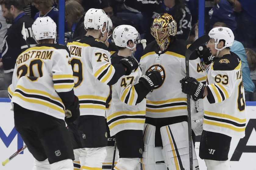 Boston Bruins goaltender Tuukka Rask (40) celebrates with teammates, left wing Brad Marchand (63), defenseman Torey Krug (47), defenseman Jeremy Lauzon (79), and center Joakim Nordstrom (20) after defeating the Tampa Bay Lightning during an NHL hockey game Tuesday, March 3, 2020, in Tampa, Fla. (AP Photo/Chris O'Meara)