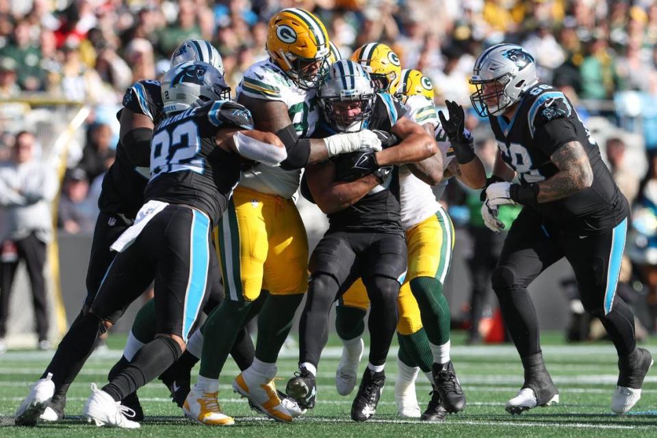 Carolina Panthers running back Chuba Hubbard (30) is flanked by Packers defense during the game at Bank of America Stadium on Sunday, December 24, 2023.