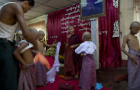 In this April 8, 2014 photo, a novice Buddhist monk, center, and a man, left, help boys to change into Buddhist robes during a "shinbyu," or ordination ceremony, at a Buddhist monastery in suburbs of Yangon, Myanmar. Though most boys only remain monks for a few days, ordination is seen as a right of passage in this predominantly Buddhist nation of 60 million. (AP Photo/Gemunu Amarasinghe)