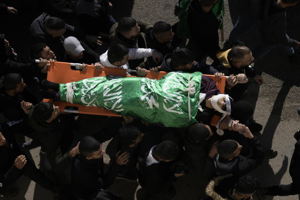 Palestinian mourners carry the body of Ahmed Daraghmeh, draped in the Hamas flag, during his funeral in the West Bank city of Nablus, Thursday, Dec. 22, 2022. Palestinian medics say Israeli forces have shot dead the 23-year-old man and wounded several others during clashes in the occupied West Bank. Daraghmeh was mortally wounded early Thursday when Palestinian militants exchanged fire with Israeli troops that entered the city of Nablus to escort Jewish worshippers to a site known as the biblical Joseph's Tomb in the Palestinian city. (AP Photo/Majdi Mohammed)