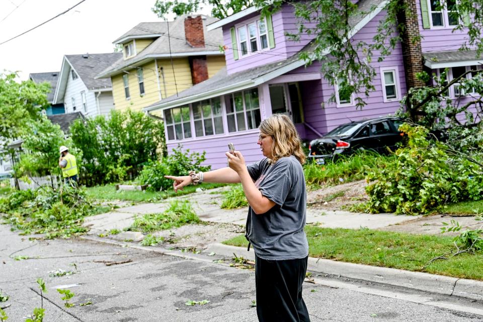 Elizabeth Tuttle accesses the damage from the overnight storm on Thursday, July 13, 2023, outside her home on Lansing's east side.
