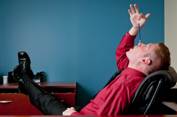 Man sitting with his feet up, balancing a pencil on his nose