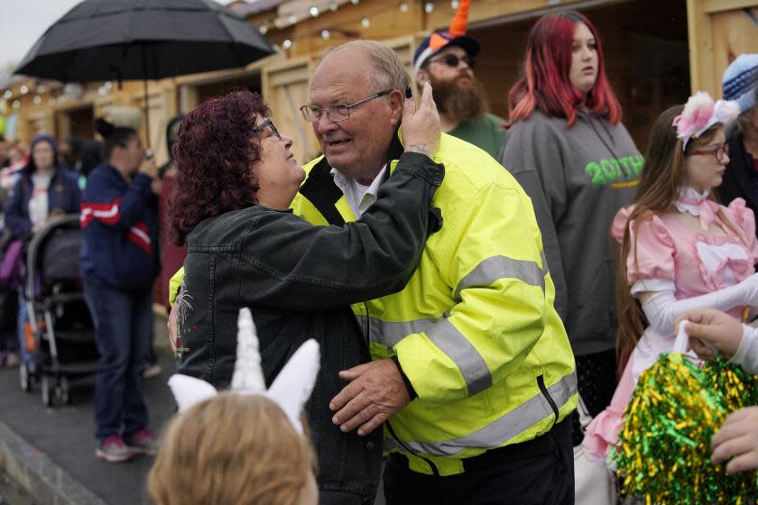 Leroy Walker, a popular city councilor, is hugged by Donna Deletetsky at a halloween event, Sunday, Oct. 29, 2023, in Auburn, Maine. Walker's son, Joseph Walker, was killed in a mass shooting while working at Schemengees Bar and Grill, Wednesday night in Lewiston, Maine. (AP Photo/Robert F. Bukaty)