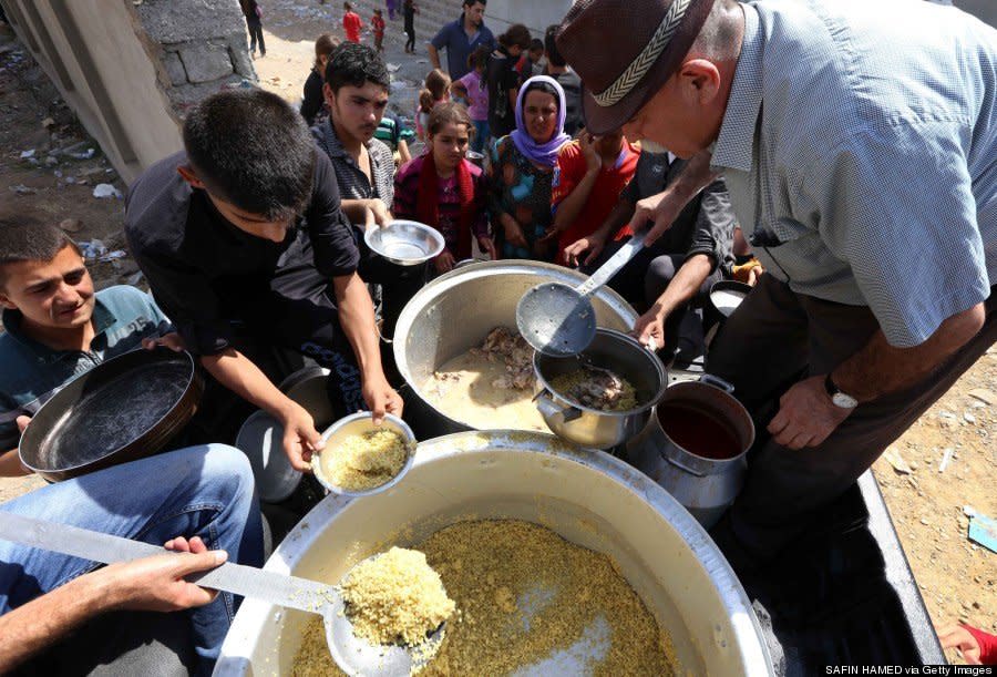 Yazidi families who fled violence in northern Iraq are given food at a school where they are taking shelter in Dohuk on August 5, 2014. (SAFIN HAMED/AFP/Getty Images)