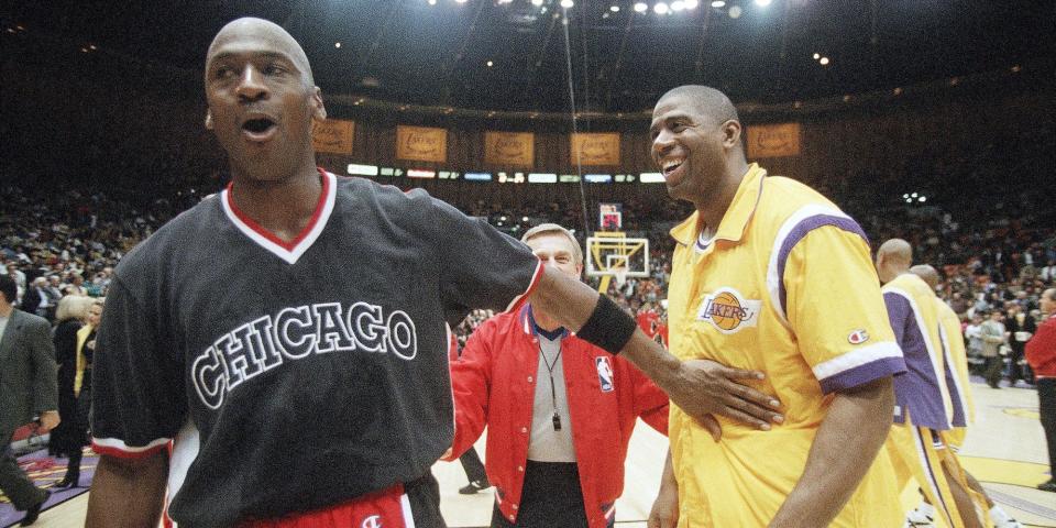 Michael Jordan smiles and pats Magic Johnson as he walks past.