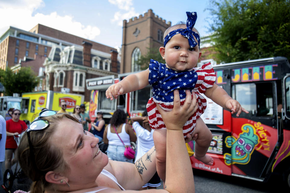 Amber Hess, lifts her daughter, Emorie Narvaez, during Harrisburg's Fourth of July Food Truck Festival at River Front Park in Harrisburg, Pa., Tuesday, July 4, 2023. (Mark Pynes/The Patriot-News via AP)