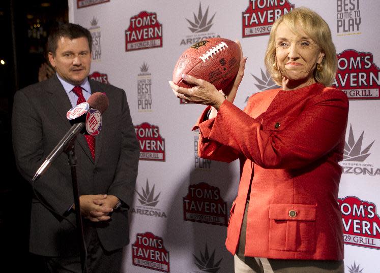 Arizona Cardinals president Michael Bidwill, left, looks on as Arizona Gov. Jan Brewer holds up a football Tuesday, Oct. 11, 2011, in Phoenix, after NFL owners awarded the 2015 Super Bowl to the Phoenix area. (AP Photo/The Arizona Republic, Michael Chow) MARICOPA COUNTY OUT NO SALES