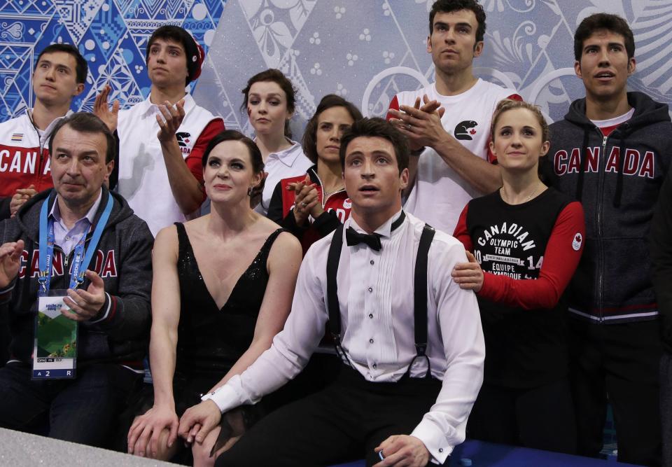 Tessa Virtue and Scott Moir of Canada look at their score with teammates and Patrick Chan (L) in the "kiss and cry" area during the Team Ice Dance Short Dance at the Sochi 2014 Winter Olympics, February 8, 2014. REUTERS/Darron Cummings/Pool (RUSSIA - Tags: SPORT FIGURE SKATING SPORT OLYMPICS)