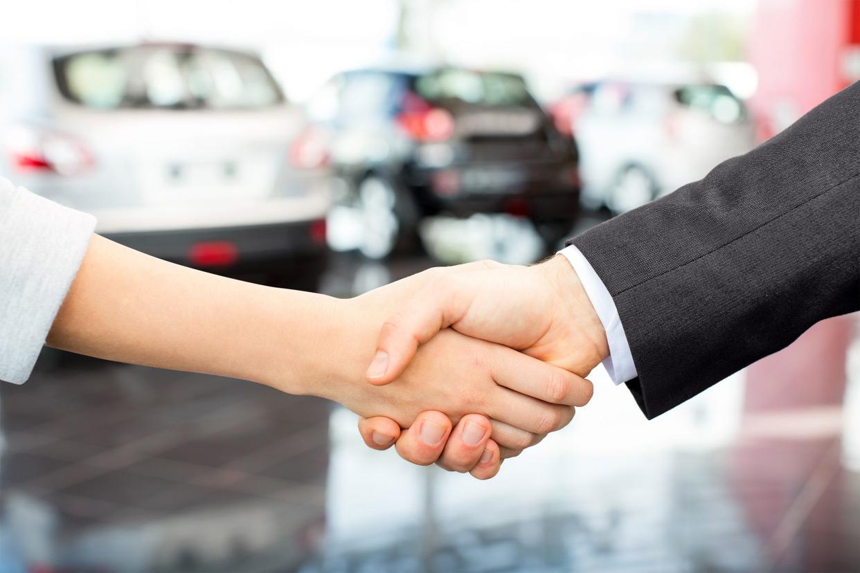 Closeup of hand shake with cars in the background