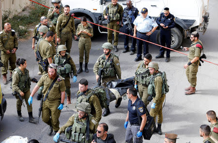 Israeli soldiers remove the dead body of a Palestinian at the scene of a stabbing attack in Hebron, in the occupied West Bank October 22, 2018. REUTERS/Mussa Qawasma