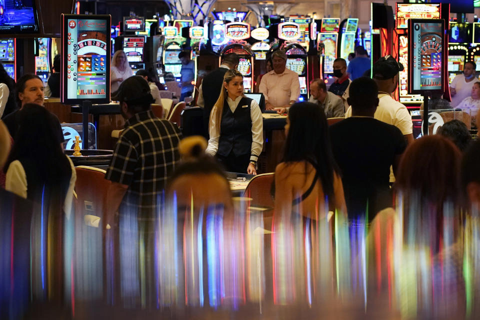 In this June 24, 2021, photo, crowds walk through the casino during the opening night of Resorts World Las Vegas in Las Vegas. Las Vegas fully reopened and lifted restrictions on most businesses June 1, though many casino-resorts had already returned to 100% capacity before that with approval from state regulators. Visitor numbers, while not at their pre-pandemic highs, have grown by double digits four months in a row. But this progress is threatened as Nevada this week saw the highest rate of new COVID-19 cases in the country. (AP Photo/John Locher)