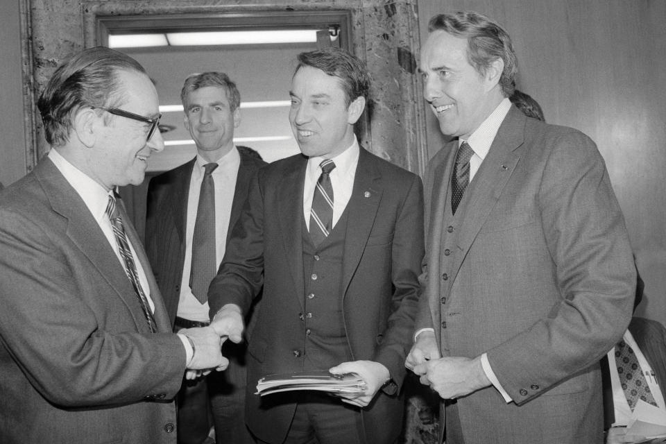 (Original Caption) Washington: Social Security Commission Chairman Alan Greenspan (L) shakes hands with Sen. Charles Grassley, R-Iowa, as Senate Finance Chairman Robert (R-Kans.,) looks on prior to a hearing on Social Security's needs. In background Sen. John Danforth, R-Mos.