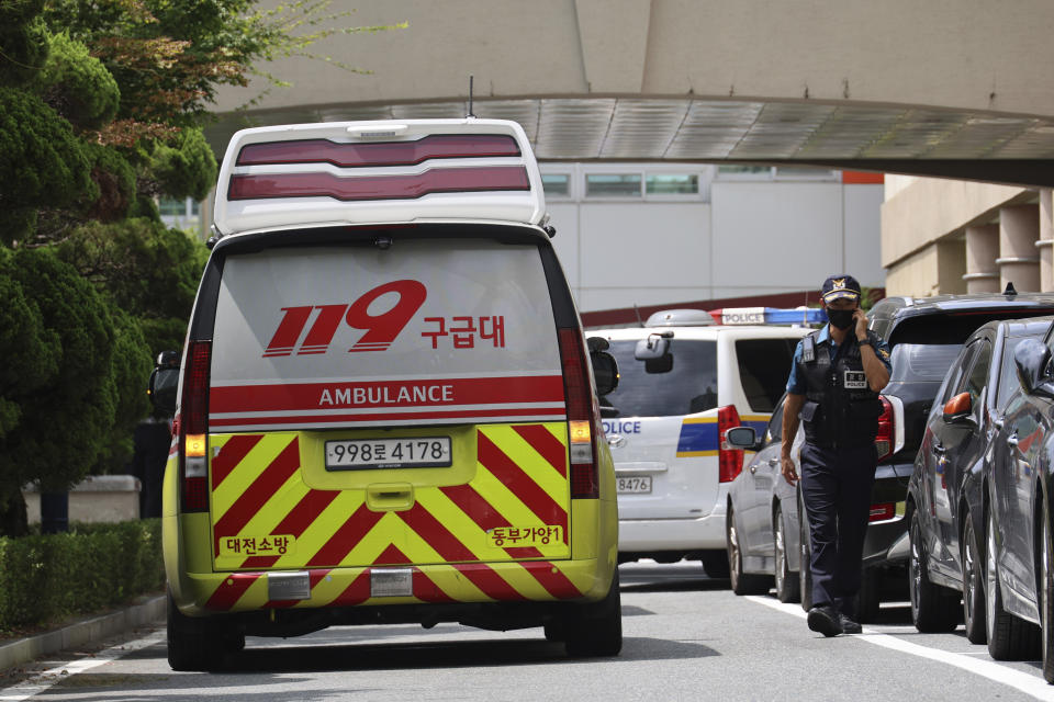 A police officer passes by an ambulance at Songchon High School in Daejeon, South Korea, Friday, Aug. 4, 2023. South Korean police are chasing the suspect in a stabbing attack in at the high school in the central city of Daejeon, a day after another stabbing incident at a shopping mall in the city of Seongnam, south of Seoul on Thursday, leaving multiple people wounded. (Kim Jun-beom/Yonhap via AP)
