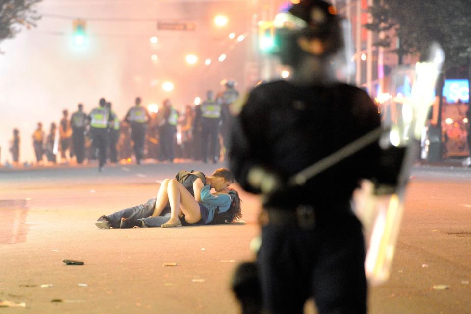 <p>Riot police walk in the street as a couple kiss on June 15, 2011 in Vancouver, Canada. Vancouver broke out in riots after their home team lost in Game Seven of the Stanley Cup Finals. </p>