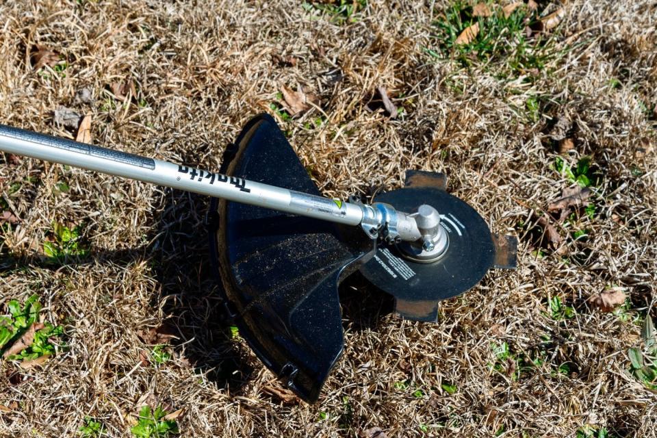 The cutting head on the Makita cordless brush cutter trimming grass and weeds to a short height.