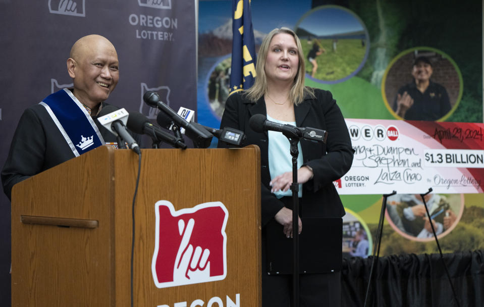 Cheng "Charlie" Saephan laughs while speaking during a press conference after it was revealed that he was one of the winners of the $1.3 billion Powerball jackpot at the Oregon Lottery headquarters on Monday, April 29, 2024, in Salem, Ore. Oregon Lottery External Communications Program Manager Melanie Mesaros listens at right. (AP Photo/Jenny Kane)