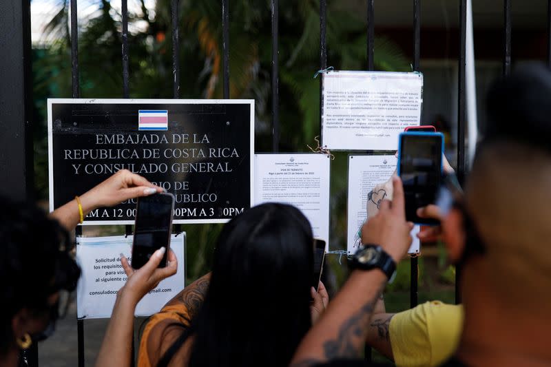 People using their mobile phones take pictures of a list with visa requirements for Cubans imposed by the country, in front of the Costa Rica embassy, in Havana