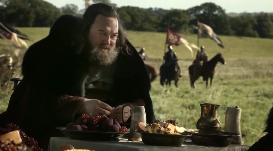 King Baratheon eating outside while soldiers approach
