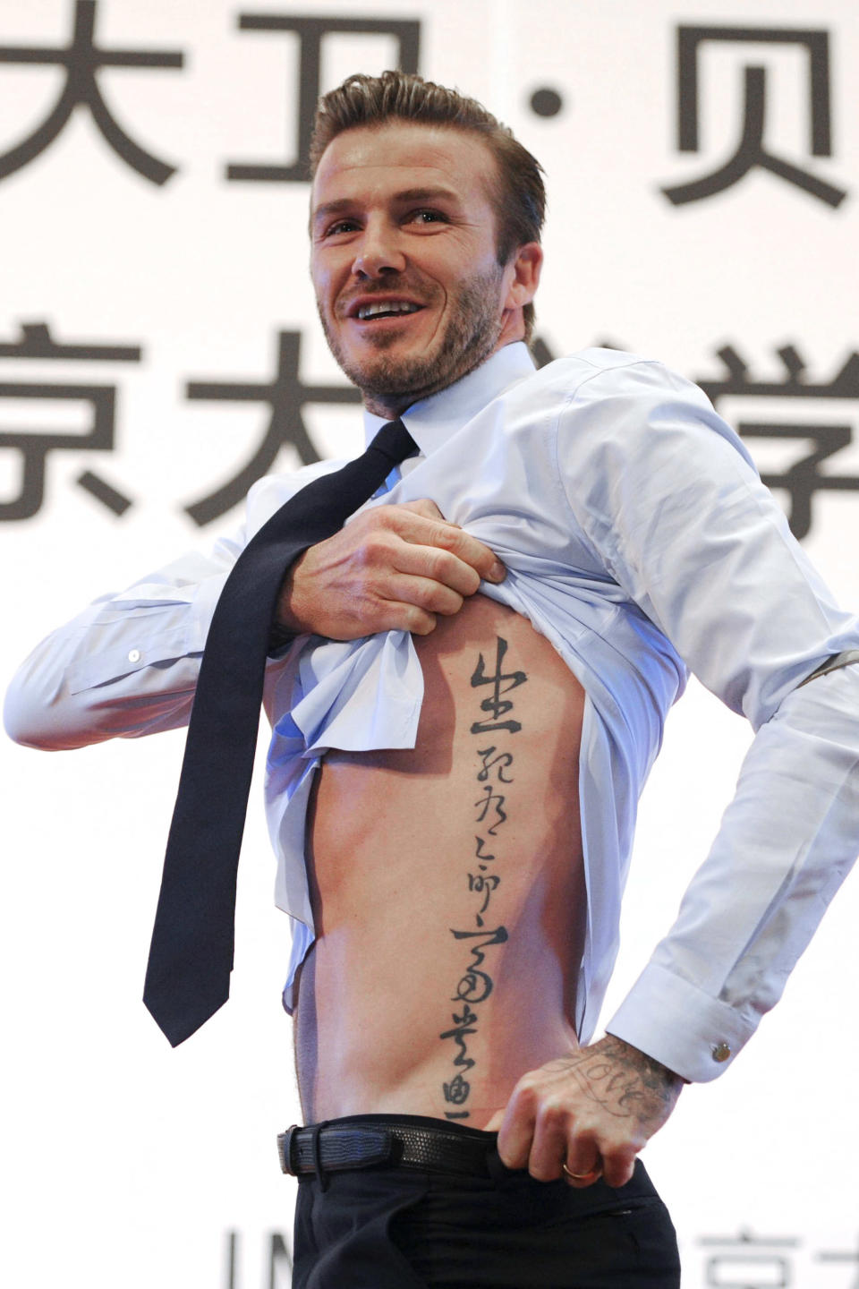 <p>David Beckham hat angeblich über 50 Tattoos, darunter auch eines mit dem Namen seiner Tochter Harper auf seinem Nacken und die Nummer 99 auf dem Handgelenk – das Jahr, als er seine Frau Victoria Beckham heiratete. Hier ist das seitliche Tattoo des ehemaligen Fußballspielers zu sehen. Es ist chinesisch ist und bedeutet: „Tod und Leben haben feste Termine, Reichtum und Ehre hängen vom Himmel ab“. <em>[Bild: Getty]</em> </p>