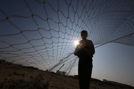 Palestinian Hamza Abu Shalhoub, 16, sets up a net to catch songbirds at the site of Gaza destroyed airport, in Rafah in the southern Gaza Strip November 8, 2018. Picture taken November 8, 2018. REUTERS/Ibraheem Abu Mustafa
