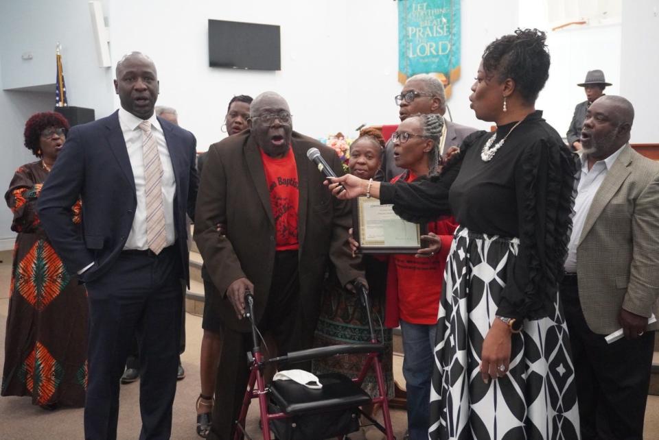 Minister Reshone Flanders, right, holds the microphone to Hopewell Baptist Church Deacon Lonnie Henley while he accepts his certificate during the Black History Month service Sunday at DaySpring Baptist Church in northeast Gainesville.
(Credit: Photo by Voleer Thomas, Correspondent)