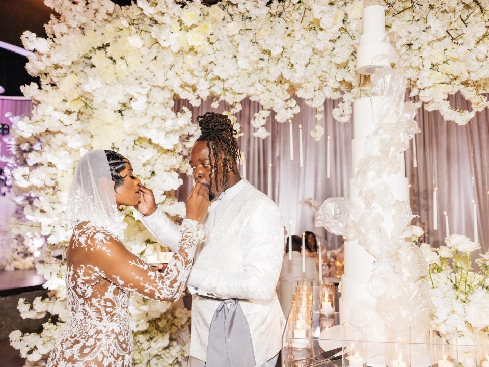 A couple feed each other cake in front of their oversized cake.